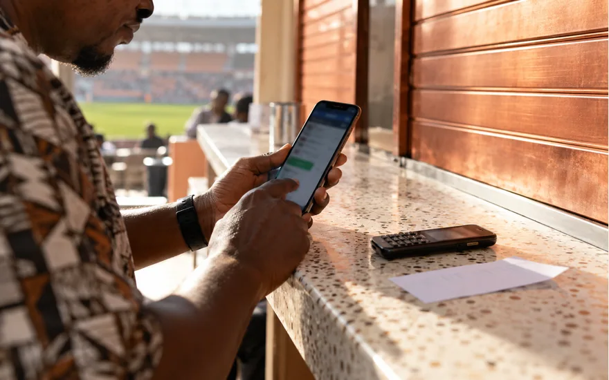 Adult checking a phone beside another handset on a cafe shelf