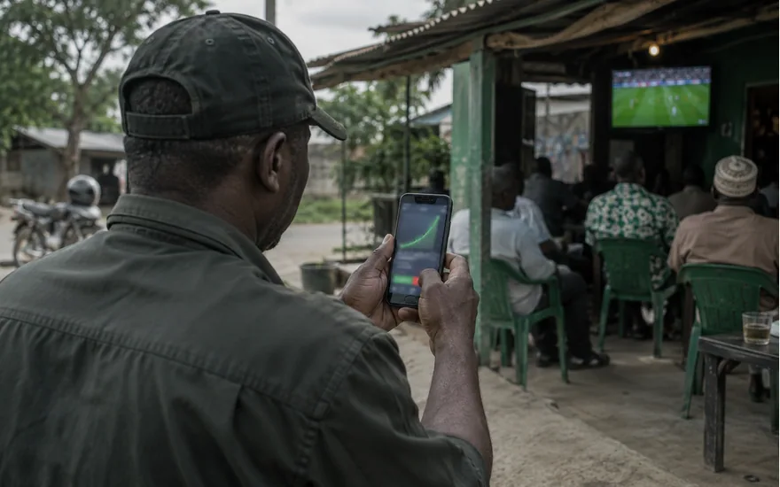 Man checking a phone outside a modest football viewing shelter