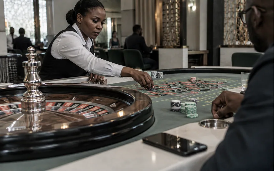Dealer arranging chips beside a roulette wheel in a quiet casino