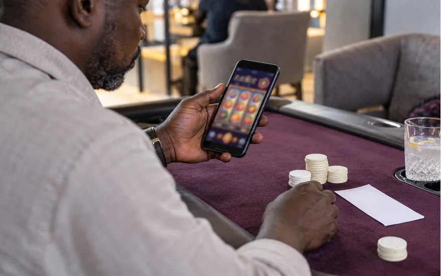 Adult comparing a phone game display with plain chips and a paper record