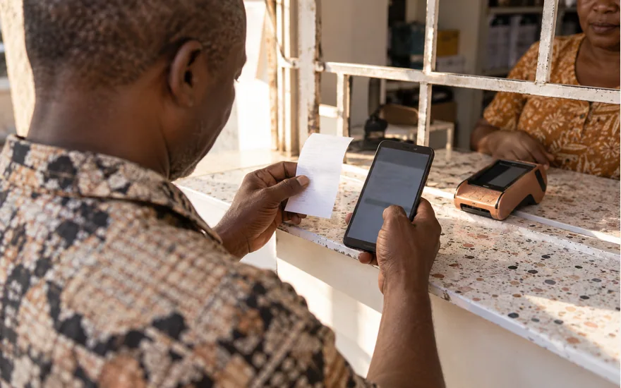 Customer comparing a phone and receipt at a stone service counter