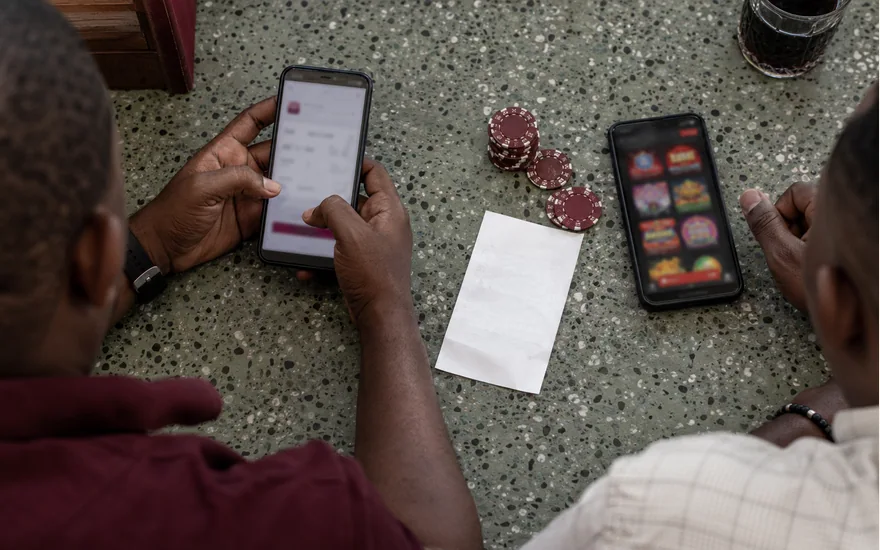 Two phones showing blurred wallet and casino screens beside chips and a receipt