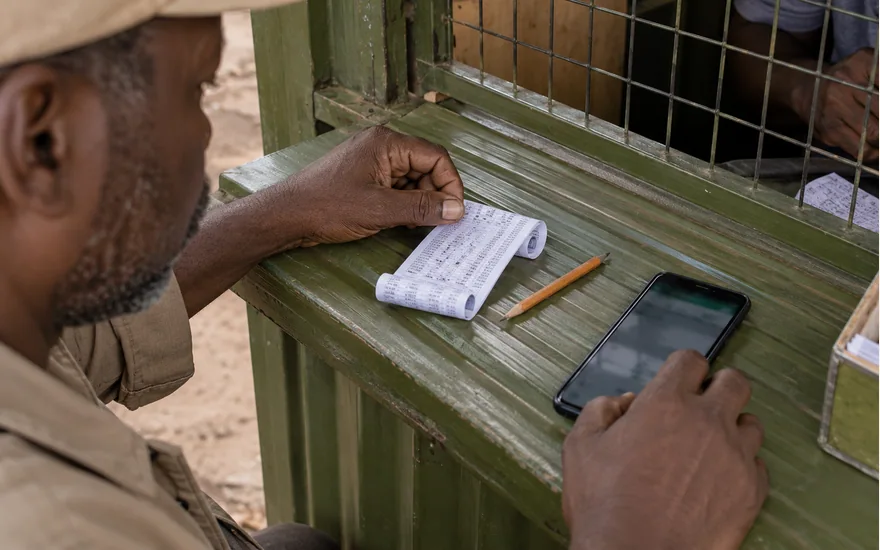 Man checking a phone beside a receipt at a green counter