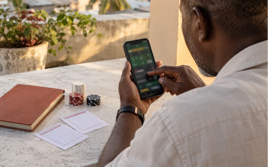 Adult reviewing a phone beside chips, papers and a plain notebook