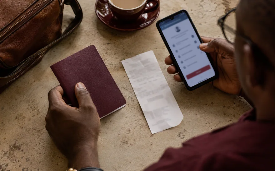 Hands beside a closed passport and phone at a tabletop